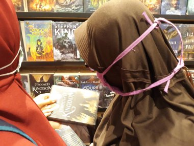 the woman is reading the book. Indonesia, rak buku di toko buku, nampak pengunjung toko buku membaca dan memilih buku yang akan dibeli. budaya membaca buku yang semakin langka dan susah ditemukan, sadar literasi, baik buku ilmiah, pelajaran, novel