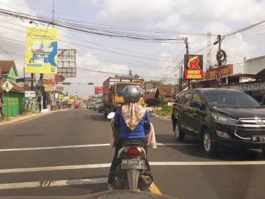 vehicles stopped at red light. Yogyakarta, Indonesia, June 5, 2023, pengemudi wanita sepeda motor berhenti di lampu lalu lintas, lampu merah, perempatan, menunggu lampu hijau menyala tanda boleh jalan