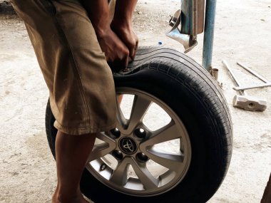 Adam arabanın tekerleğini değiştiriyor. 