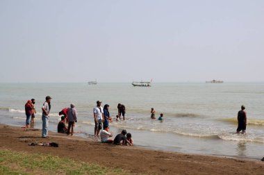 Sahildeki bir teknede insanlar. 