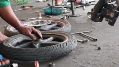 Motosiklet tekerleklerini tamir eden tamirci. Motosiklet tekerleğini bağlıyorum..