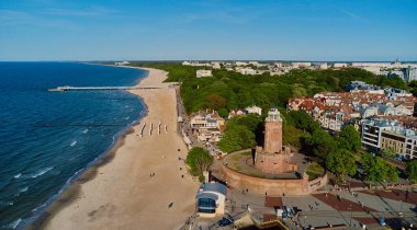 Kolobrzeg, Polonya 'daki deniz feneri ve limanın güneşli gününde insansız hava aracı görüntüsü.