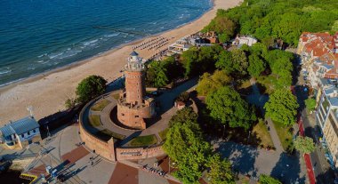 Kolobrzeg, Polonya 'daki deniz feneri ve limanın güneşli gününde insansız hava aracı görüntüsü.