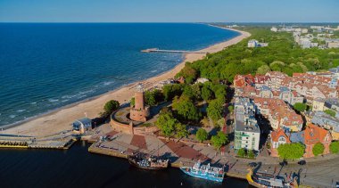 Kolobrzeg, Polonya 'daki deniz feneri ve limanın güneşli gününde insansız hava aracı görüntüsü.