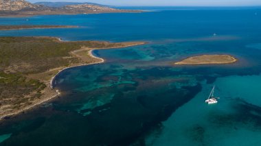 Stintino yakınlarındaki Isola Piana adasının ve Spiaggia La Pelosa plajının havadan çekilmiş fotoğrafı. Dağlık ada, mavi su ve berrak gökyüzü. Sardinya 'nın kuzeybatı kısmı, Sassari ili, İtalya.