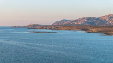 Stintino yakınlarındaki Isola Piana adasının ve Spiaggia La Pelosa plajının havadan çekilmiş fotoğrafı. Dağlık ada, mavi su ve berrak gökyüzü. Sardinya 'nın kuzeybatı kısmı, Sassari ili, İtalya.