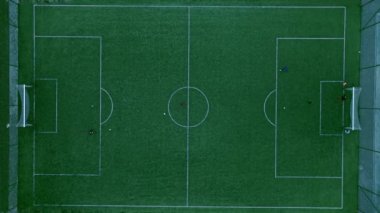 Yükselen drone atışları, yukarıdaki bir futbol sahasının güzelliğini yakalıyor. Oyuncular heyecanlı bir maça girerken büyüleyici bir dans sergiliyor..