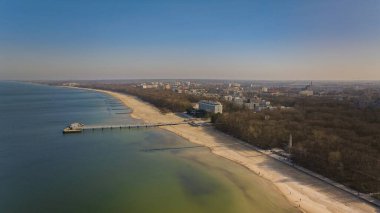 Kolobrzeg iskelesi güneşli bir şubat öğleden sonra. Rüzgarsız hava, tek bir dalga olmadan sakin deniz, rıhtımda gezinen turistler. Serin atmosfer, bir stok fotoğrafında yakalandı..
