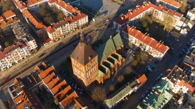 Koszalin şehir merkezini altın ışıkla kaplayan bir drone çekimi, katedralin, Zafer Sokağı ve belediye binasının görüntülerini içeriyor..