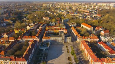 Koszalin şehir merkezini altın ışıkla kaplayan bir drone çekimi, katedralin, Zafer Sokağı ve belediye binasının görüntülerini içeriyor..