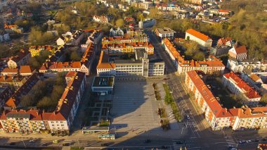 Koszalin şehir merkezini altın ışıkla kaplayan bir drone çekimi, katedralin, Zafer Sokağı ve belediye binasının görüntülerini içeriyor..