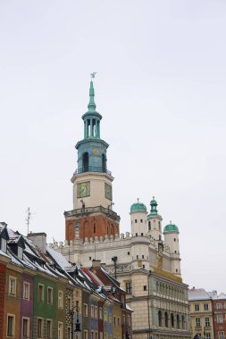 Poznan, Polonya 'daki eski pazar meydanının fotoğrafı, Ocak ayında kış aylarında çekildi. Karla kaplı çatılar, tarihi belediye binası beyaz bir gökyüzü zeminine karşı..