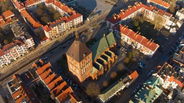 Koszalin şehir merkezini altın ışıkla kaplayan bir drone çekimi, katedralin, Zafer Sokağı ve belediye binasının görüntülerini içeriyor..