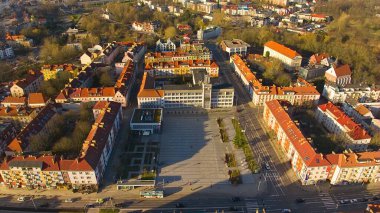 Koszalin şehir merkezini altın ışıkla kaplayan bir drone çekimi, katedralin, Zafer Sokağı ve belediye binasının görüntülerini içeriyor..