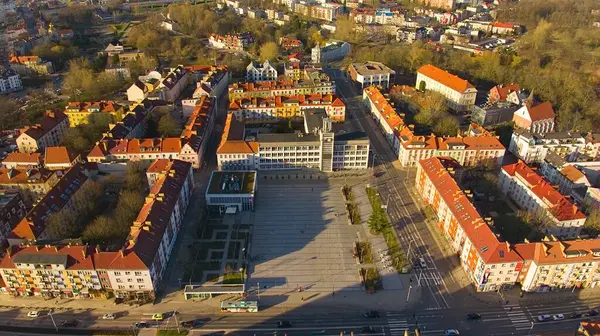 Koszalin şehir merkezini altın ışıkla kaplayan bir drone çekimi, katedralin, Zafer Sokağı ve belediye binasının görüntülerini içeriyor..