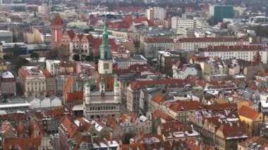 Poznan 'ın Ocak ayındaki tarihi pazar meydanının çarpıcı hava manzarası. Karla kaplı çatılar, ikonik belediye binası ve meydandaki turuncu çatılı tarihi binalar..
