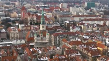 Poznan 'ın Ocak ayındaki tarihi pazar meydanının çarpıcı hava manzarası. Karla kaplı çatılar, ikonik belediye binası ve meydandaki turuncu çatılı tarihi binalar..