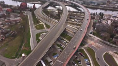 Hızlandırılmış insansız hava aracı görüntüleri Polonya 'nın Szczecin kentinde Trasa Zamkowa' yı gösteriyor, gündüz trafiği yoğunlaşıyor ve Odra Nehri 'ne bakıyor.