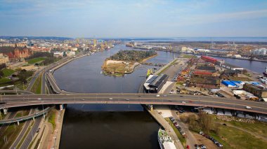 March aerial drone footage captures Szczecin's Odra River, Szczecin Castle Route, cars, Waly Chrobrego, National Museum, Provincial Office building, Port of Szczecin, docked ships, cranes, port infrastructure, and Grodzka Island. clipart