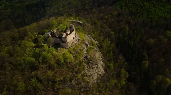 stock image An aerial view captures the medieval Chojnik Castle atop a mountain in the Karkonosze range. The ancient fortress stands proudly amidst the scenic landscape, blending history with nature.