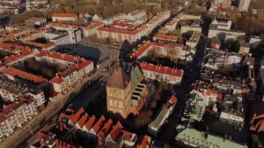 Koszalin 'in hava görüntülerinde başlıca simgeler yer alıyor: Zafer Sokağı, Ratusz ve Gotik katedral. Hava aracı güneşli bir öğleden sonra şehrin enerjisini yakalar..