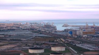 Bir İHA, Livorno 'daki rafineriyi dumanı tüten bacalar, tank altyapısı ve bulutlu gökyüzünün altında feribotlarla yakalar..