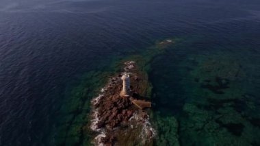 Sardinias Faro Mangiabarche sakin mavi sulara ve engebeli kayalık kıyılara bakar. İnsansız hava aracı görüntüleri, büyüleyici zıtlıklarını ve sakin güzelliğini parlak güneş ışığı altında, yumuşak dalgaların altında yakalar..
