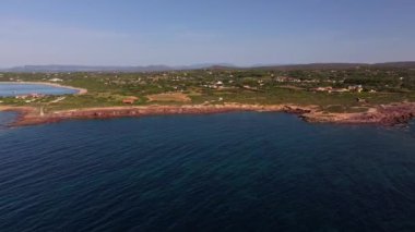 Sant 'Antioco' nun kayalık çıkıntısı Faro Mangiabarche ile güneşli gökyüzü altında sakin mavi suların ve engebeli arazinin nefes kesici zıtlıkları sunuyor..