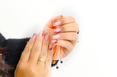 A stylish manicure: pink nails with shimmering leaf accents, paired with gold rings and Baltic amber bracelets, highlighting elegant hands and a taste for natural stone accessories. clipart