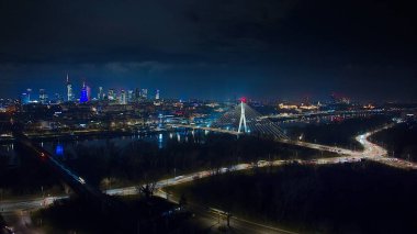 WarsawPGE Narodowy, witokrzyski Köprüsü ve aydınlık şehrin üzerinde parlayan gökdelenlerin insansız hava aracı görüntüsü.