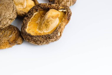 Saf beyaz arka planda, kurutulmuş shiitake mantarları sanatsal bir düzende sergilenir, engebeli dokuları ve derin umami tonları aşçılık geleneğine bir bakış sunar..