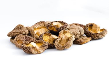 Çarpıcı bir görüntü beyaz arka planda kurumuş shiitake mantarlarını gösteriyor, onların engebeli dokularını ve doğal yemek pişirme geleneğini anlatan derin organik renkleri vurguluyor..