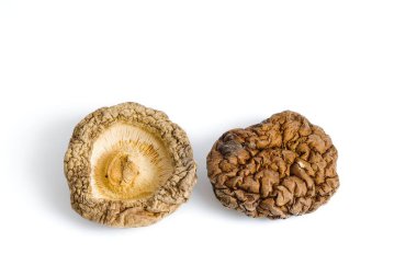 Kurumuş Şiitake mantarlarının beyaz üzerindeki bu detaylı görünümü, bu mutfak malzemesinin otantik güzelliğini yansıtan engebeli dokularını ve sıcacık, topraksı tonlarını vurgular..