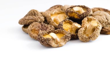 Kıtır beyaz bir yüzeyde, kurutulmuş shiitake mantarları ayrıntılı dokuları ve sıcak toprak renklerini ortaya çıkararak geleneksel mutfak malzemelerinin ilgi çekici bir görüntüsünü oluşturur..