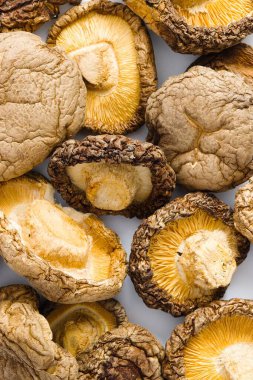 Saf beyaz arka planda, kurutulmuş shiitake mantarları sanatsal bir düzende sergilenir, engebeli dokuları ve derin umami tonları aşçılık geleneğine bir bakış sunar..