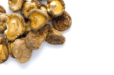 Bu resim, hem geleneği hem de sofistike mutfağı çağrıştıran, detaylı dokuları ve derin toprak tonlarıyla beyaz bir zemin üzerinde zarif bir şekilde düzenlenmiş kurutulmuş shiitake mantarlarını içeriyor..