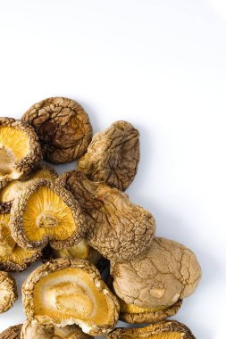 Temiz beyaz bir arkaplanda, kurumuş shiitake mantarları, dokulu yüzeylerini ve zengin doğal renklerini vurgulamak için düzenlenir ve bu gurme içeriğine sanatsal bir bakış sunar..