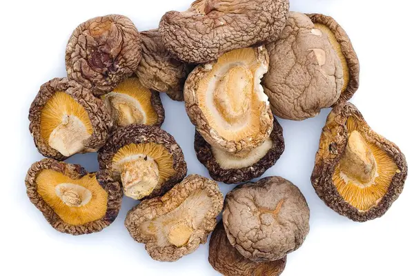 Bu canlı görüntü, geleneksel bir mutfak malzemesinin orijinalliğini sembolize ederek, kaba dokularını ve zengin toprak tonlarını yakalayan, beyaz üzerinde kurutulmuş shiitake mantarları barındırıyor..