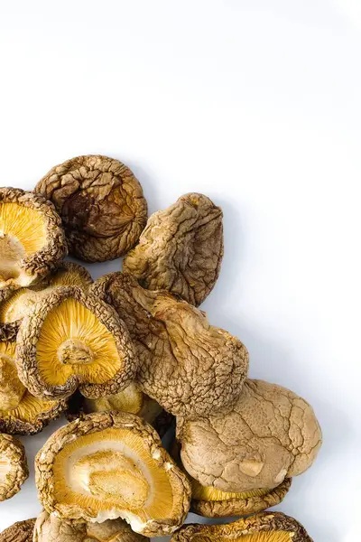 Temiz beyaz bir arkaplanda, kurumuş shiitake mantarları, dokulu yüzeylerini ve zengin doğal renklerini vurgulamak için düzenlenir ve bu gurme içeriğine sanatsal bir bakış sunar..