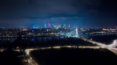 Varşova 'nın canlı gökdelenlerinin, köprülerin ve gece enerjisiyle parıldayan sokakların hava görüntüsü..