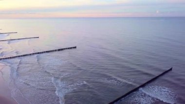 Gün batımında Ustronie sahilinin kış manzarası. Sakin deniz, ılık renkler, kar yok sadece huzurlu dalgalar ve altın saat boyunca yakalanan sakin bir ufuk..