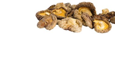 Beyaz bir zemin üzerinde kurumuş shiitake mantarlarının yakın plan görüntüsü, bu geleneksel, umami paketlenmiş bileşenin özünü yakalayarak, toprak kahverenginin her kırışıklığını ve tonunu ortaya çıkarır..