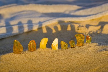 Kolobrzegs kumlu sahilinde, balın gölgesinde parlayan kehribar gün batımının sıcaklığını yansıtıyor..