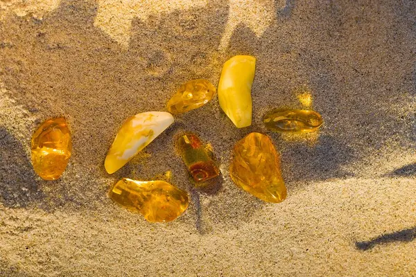 Baltık kehribar taşları, Kolobrzeg 'de batan güneşin altın ışıklarıyla renklenen ılık kumda hafifçe parıldıyor..