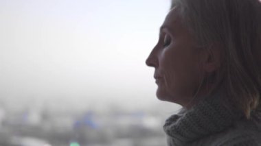 Düşünceli depresif kadın pencerenin yanında zor kararlar vermeye çalışıyor.