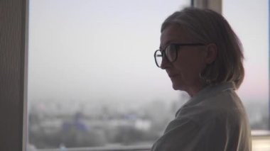 Beyaz üniformalı ciddi kadın doktor hastayı dinliyor ve pencereye bakıyor.