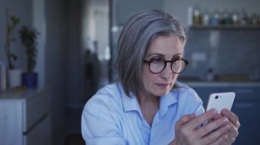 Gri saçlı, ciddi bir kadın patron. Çalışanlarının raporlarını akıllı telefondan kontrol ediyor. İşindeki hatalar yüzünden deliriyor ve görevlerini ve görevlerini yerine getiremiyor.