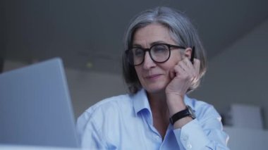 Dizüstü bilgisayarda dizayn projesi üzerinde çalışan son sınıf öğrencisi gülümseyerek işini zevkle yapıyor.