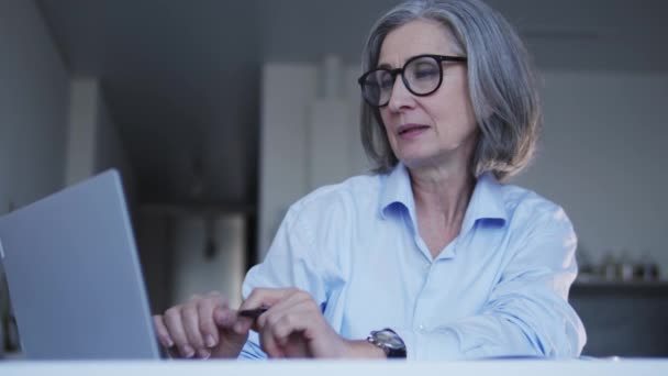 Olgun Gri Saçlı Gözlüklü Bir Kadını Laptopta Yabancı Ortaklarla Yazışıyor — Stok video