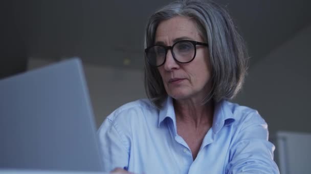 白发苍苍的女人在笔记本电脑和医疗器械上工作时感到脖子疼痛 — 图库视频影像